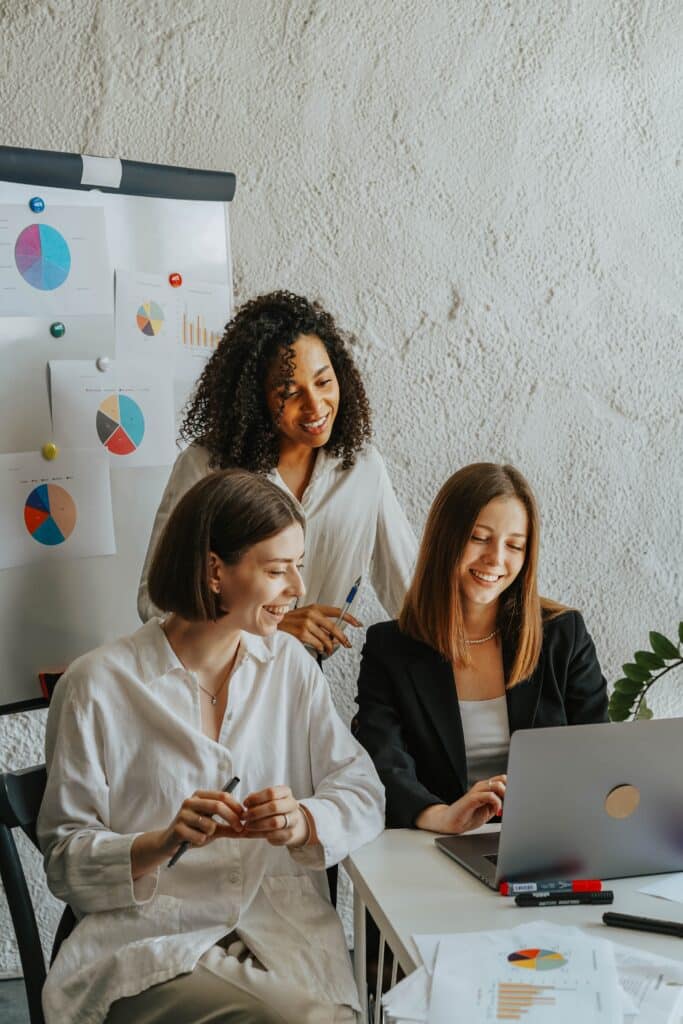 women in the office looking at a laptop screen and smiling