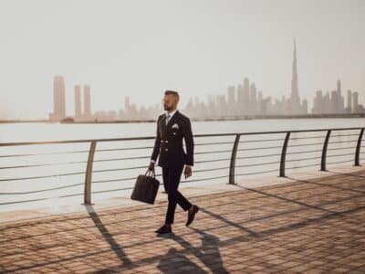 entrepreneur walking along a river with cityscape in background